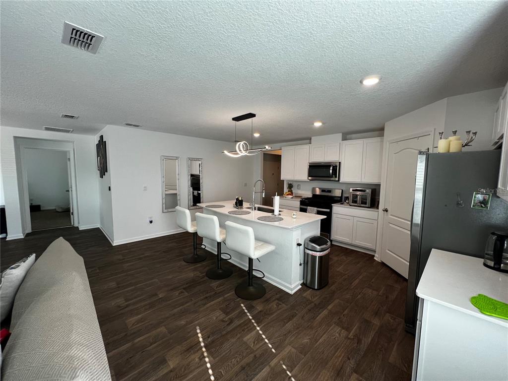 A kitchen with white cabinets, a central island with bar seating, and dark wood flooring — 319 ARDILA CIRCLE, ST AUGUSTINE, FL