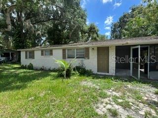 A single-story house with white siding, a brown door, and a screened-in porch — 404 W LUTZ LAKE FERN ROAD, LUTZ, FL