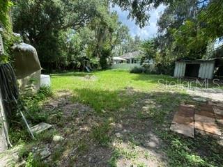 A single-story white house with a screened porch and a grassy yard under a blue sky — 404 W LUTZ LAKE FERN ROAD, LUTZ, FL
