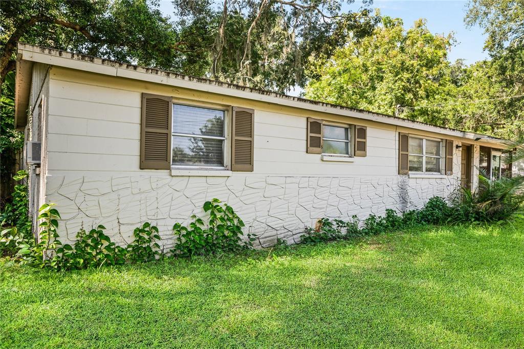 A single-story house exterior features white horizontal siding, stone-patterned lower walls, and brown shutters — 404 W LUTZ LAKE FERN ROAD, LUTZ, FL