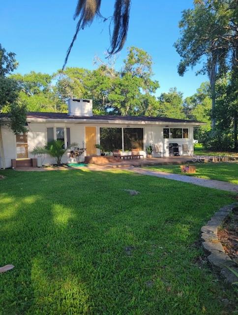 A single-story house with a white exterior, large windows, and a patio sits on a lawn — 9434 BEAR LAKE ROAD, APOPKA, FL