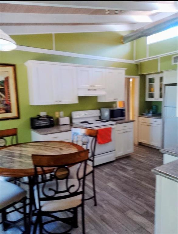 A kitchen with green walls, white cabinets, a white stove, and a round dining table — 9434 BEAR LAKE ROAD, APOPKA, FL