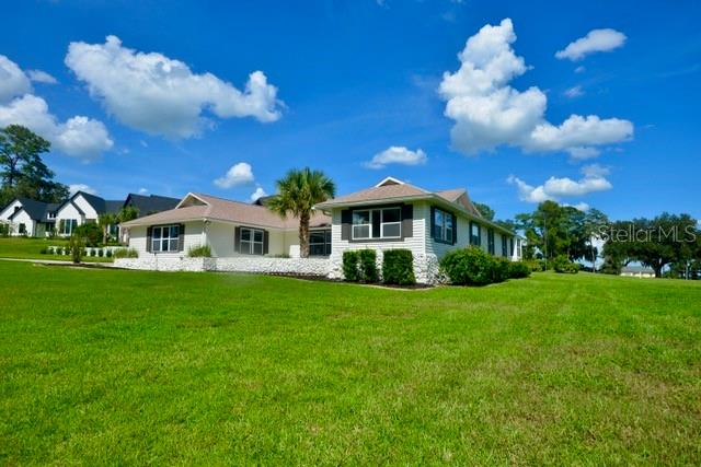 A living room features a vaulted ceiling with exposed beams, a stone fireplace, and furniture — 5391 NW 76TH COURT, OCALA, FL