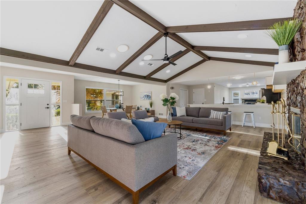 A modern kitchen features white cabinets, quartz countertops, a tile backsplash, and three bar stools — 5391 NW 76TH COURT, OCALA, FL
