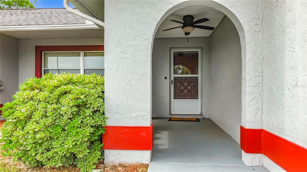 The exterior of a house features a white stucco wall, a red accent stripe, and an arched entryway — 230 W STAGGERBUSH PATH, BEVERLY HILLS, FL