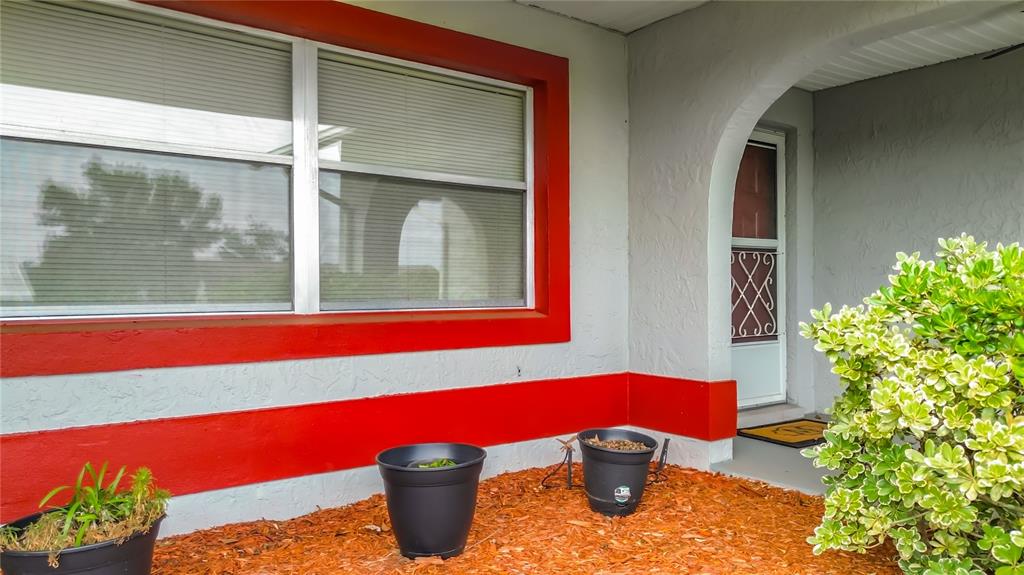 A house exterior features a red-trimmed window, a gray arched entryway, and potted plants — 230 W STAGGERBUSH PATH, BEVERLY HILLS, FL