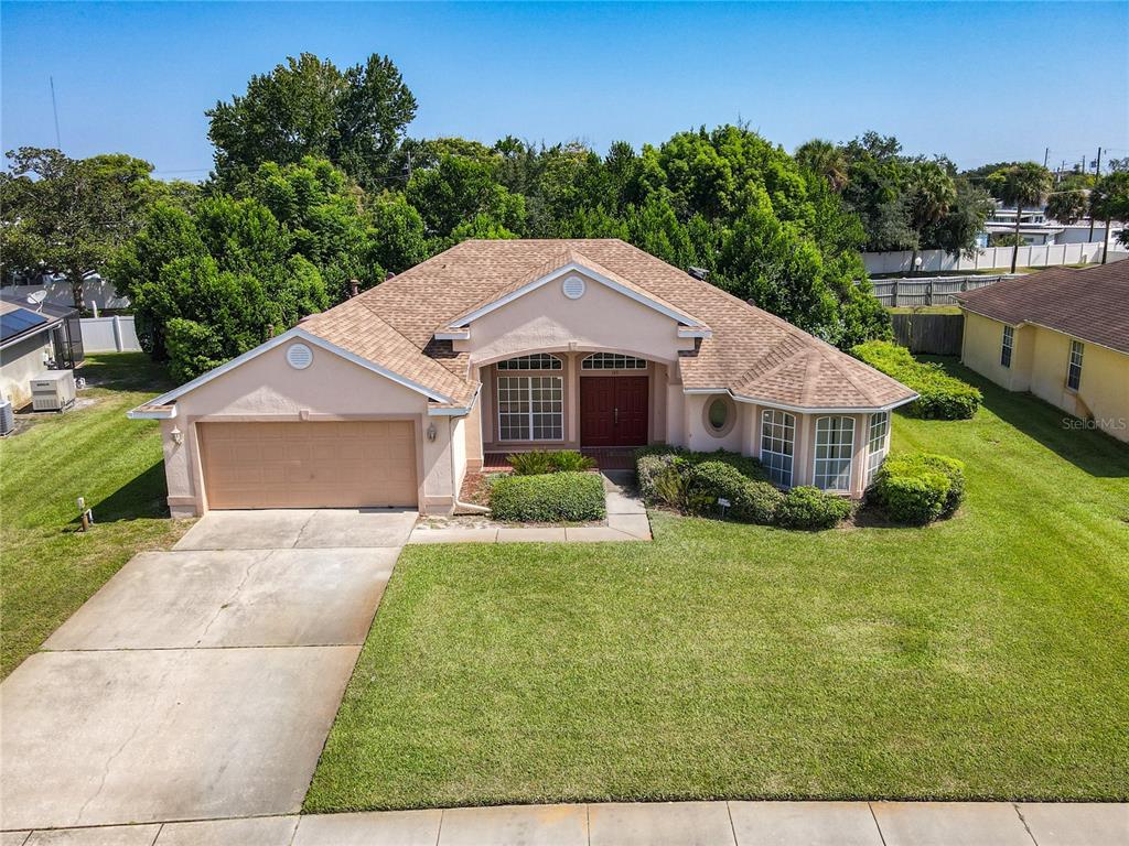 An aerial view of a single-story suburban house with a tan exterior and two-car garage — 145 NEEDLEWOOD LOOP, DEBARY, FL
