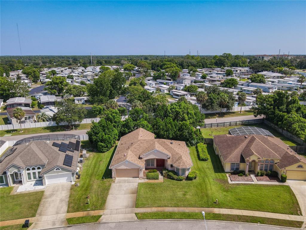 An aerial view shows three suburban houses with brown roofs and green lawns — 145 NEEDLEWOOD LOOP, DEBARY, FL