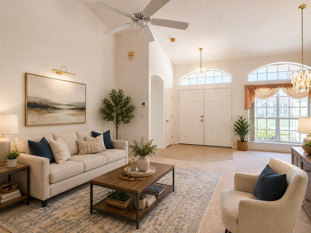 A living room with a vaulted ceiling, ceiling fan, beige sofa, and a large front entryway — 145 NEEDLEWOOD LOOP, DEBARY, FL