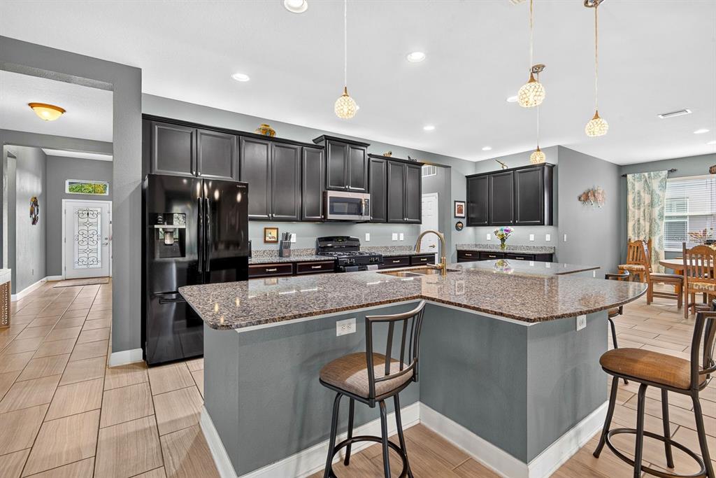 A kitchen features dark cabinets, granite countertops, a central island, and tile flooring — 792 ROSEMARY CIRCLE, BRADENTON, FL