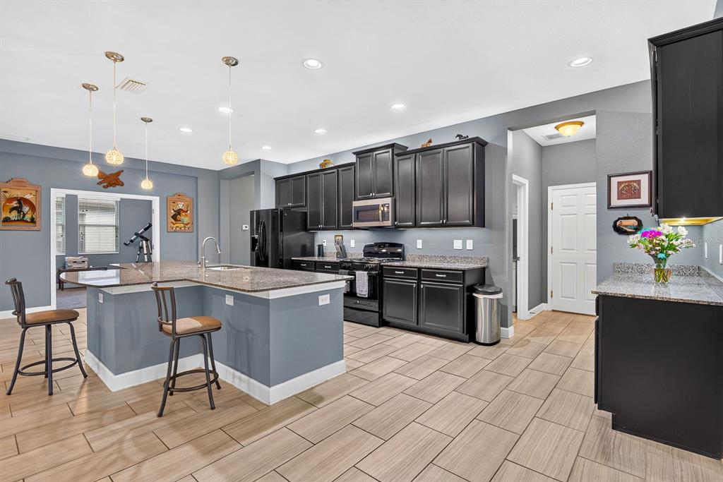 A kitchen features dark cabinets, granite countertops, a central island with seating, and tile flooring — 792 ROSEMARY CIRCLE, BRADENTON, FL