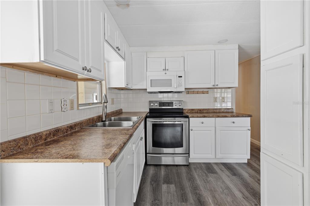 A kitchen features white cabinets, a stainless steel oven, and brown laminate countertops — 3417 WAX MYRTLE CIRCLE, ZELLWOOD, FL