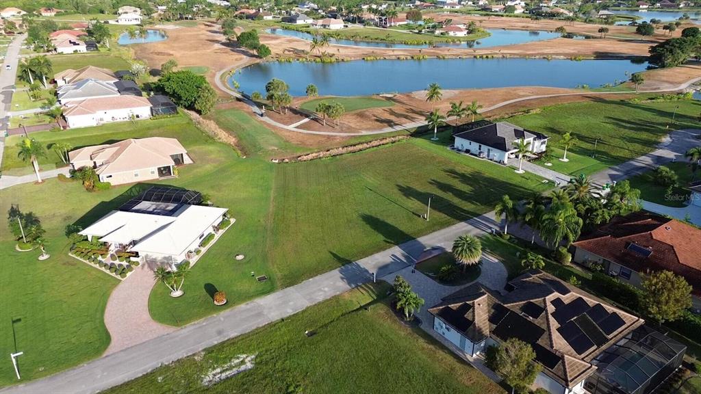 An aerial view shows a vacant residential lot situated between several houses near a golf course — 18001 BLUEWATER DRIVE, NAPLES, FL