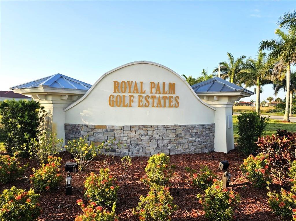 A stone-based monument sign for Royal Palm Golf Estates stands in a landscaped garden — 18001 BLUEWATER DRIVE, NAPLES, FL