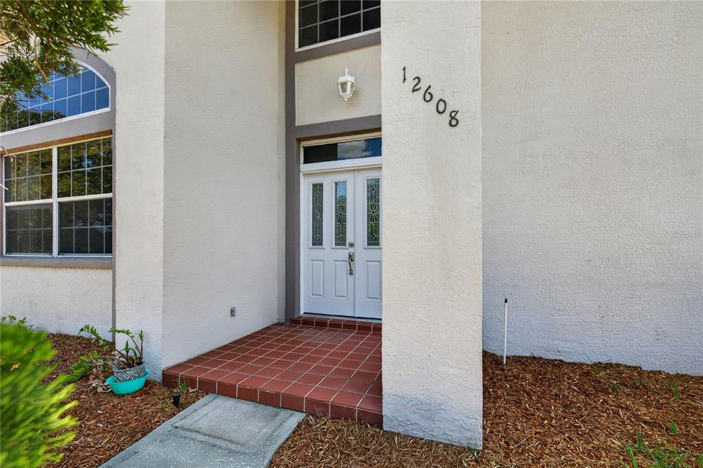 The exterior of a house features a white double door entrance with a tiled porch — 12608 LAKE RIDGE CIRCLE, CLERMONT, FL
