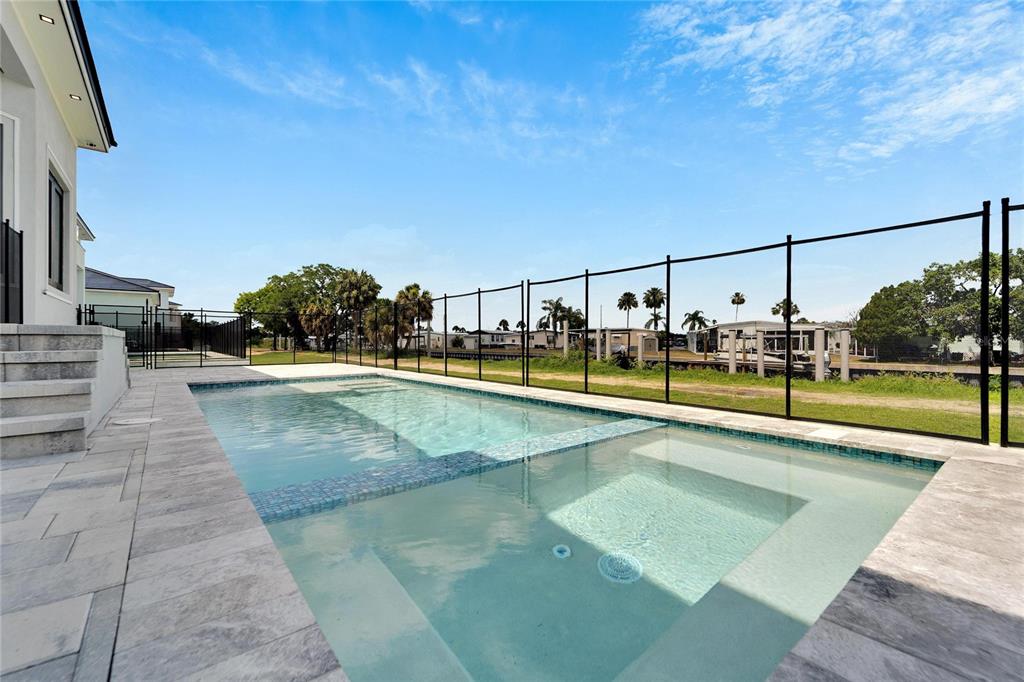 A rectangular swimming pool with a tanning ledge sits on a patio beside a house — 6540 SIMONE SHORES CIRCLE, APOLLO BEACH, FL