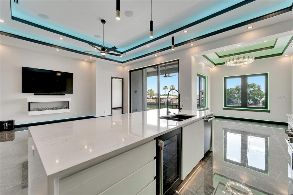 A modern kitchen features a large white quartz island, dark tile floors, and recessed lighting — 6540 SIMONE SHORES CIRCLE, APOLLO BEACH, FL
