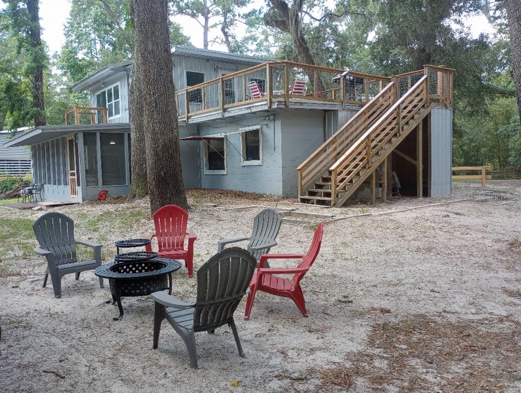 A two-story house with a large wooden deck, exterior stairs, and a fire pit area — 348 NW NULL ROAD, WHITE SPRINGS, FL