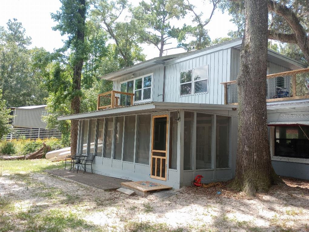 A two-story house with a screened-in porch and upper-level wooden decks sits among trees — 348 NW NULL ROAD, WHITE SPRINGS, FL