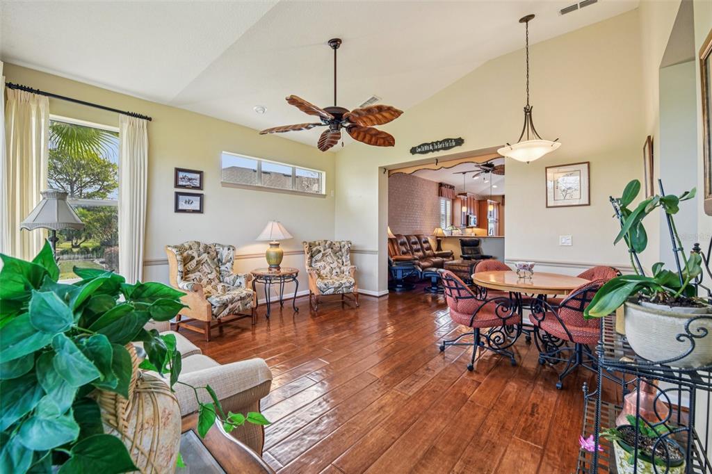A living room features a brick wall, leather furniture, wood flooring, and a ceiling fan — 8013 PINE HOLLOW DRIVE, MOUNT DORA, FL