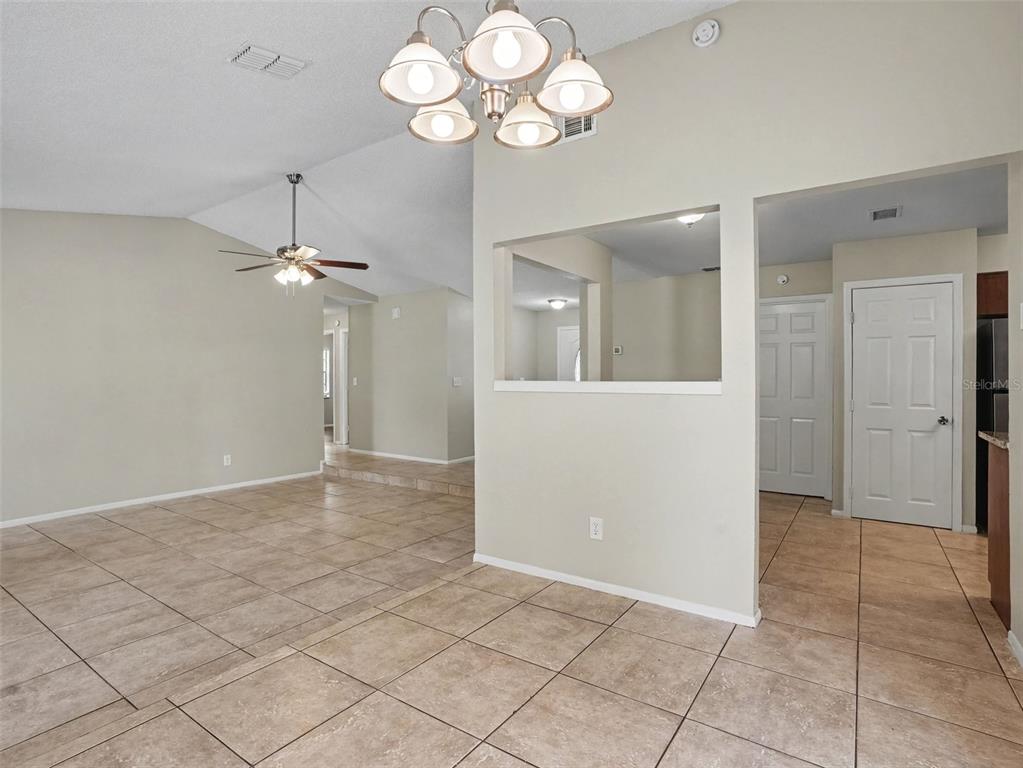 An interior view shows a tiled dining area with a chandelier and a pass-through window — 3329 FOX RIDGE DRIVE, WINTER HAVEN, FL