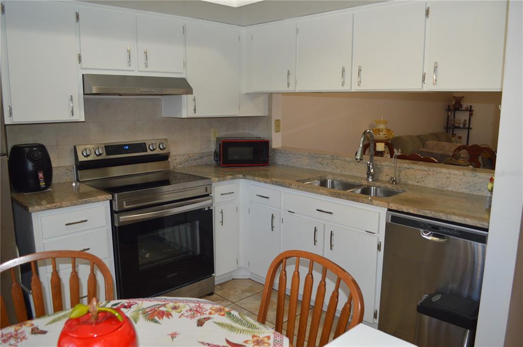 A kitchen features white cabinets, stainless steel appliances, and granite countertops — 38359 IRONWOOD PLACE UNIT 38359, ZEPHYRHILLS, FL