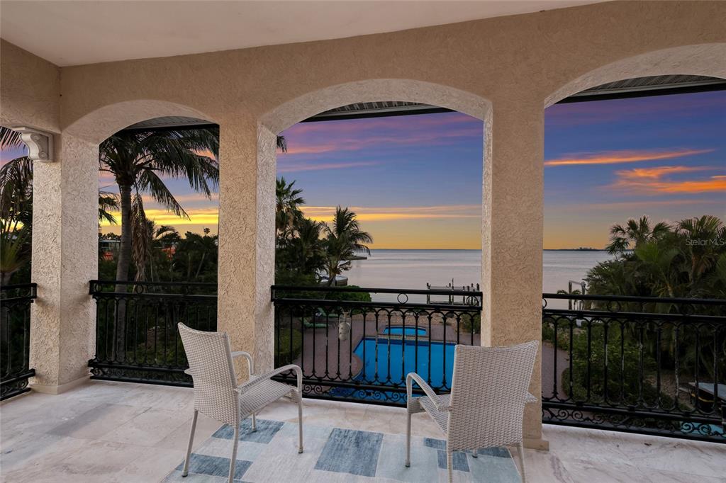 A balcony with two chairs overlooks a swimming pool and a sunset over the water — 518 58TH STREET, HOLMES BEACH, FL