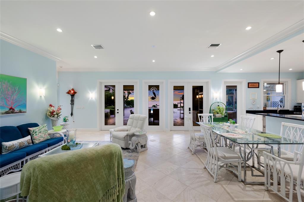 A bright open-concept living and dining area features light blue walls, tile floors, and glass doors — 518 58TH STREET, HOLMES BEACH, FL