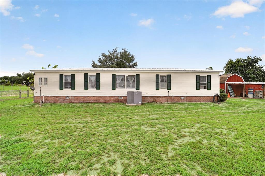 A single-story manufactured home with beige siding and green shutters sits on a grassy lot — 15355 SE 113TH STREET ROAD, OCKLAWAHA, FL
