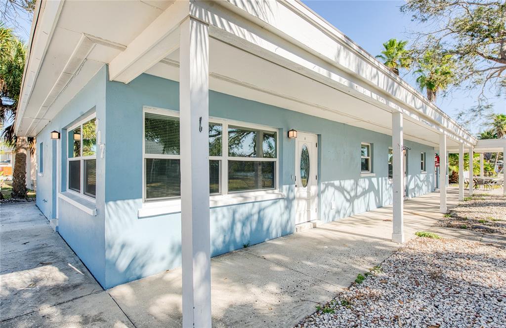 A light blue single-story building exterior features a covered concrete walkway and multiple white doors — 717 E GULF BOULEVARD UNIT 3, INDIAN ROCKS BEACH, FL