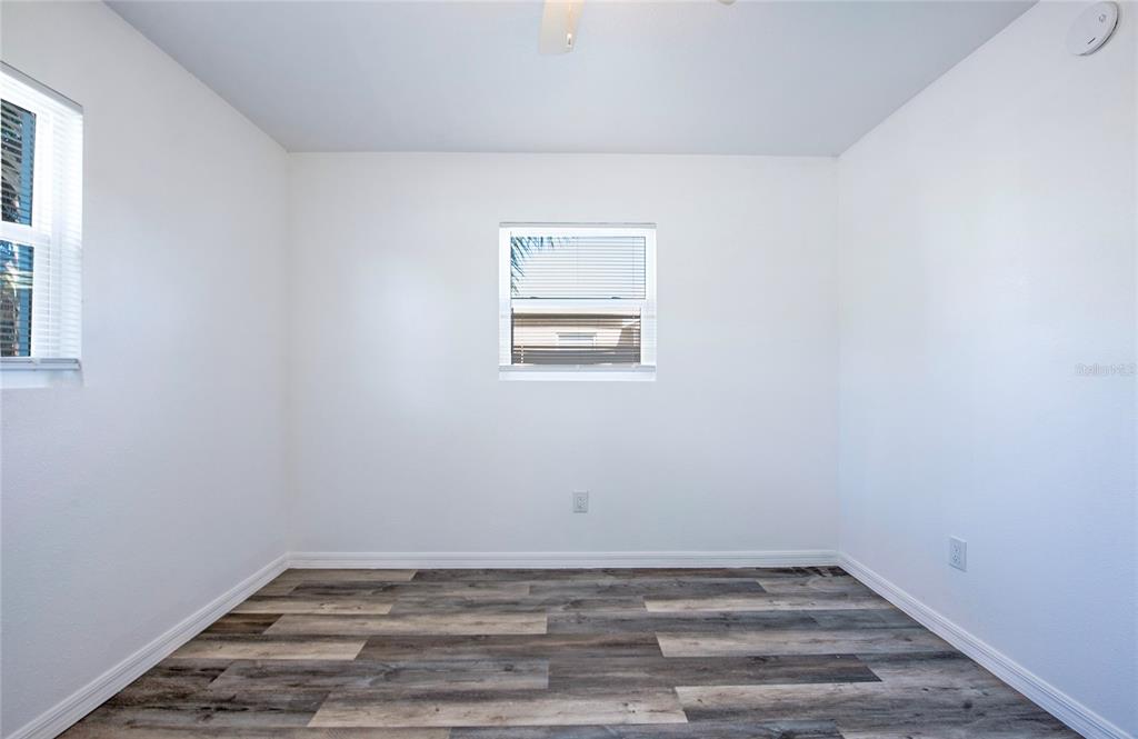 An empty bedroom features white walls, wood-look laminate flooring, and two windows with blinds — 717 E GULF BOULEVARD UNIT 3, INDIAN ROCKS BEACH, FL