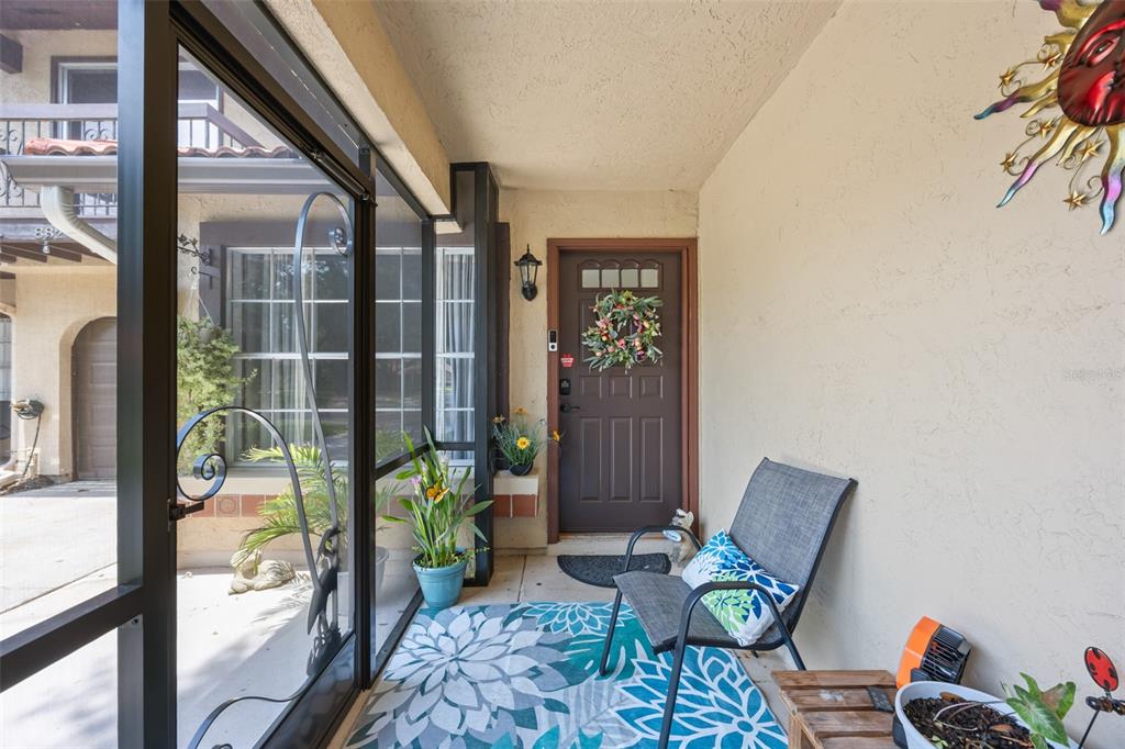 A screened-in front porch features a brown door, a patterned rug, and a patio chair — 898 BROW COURT NE, PALM BAY, FL