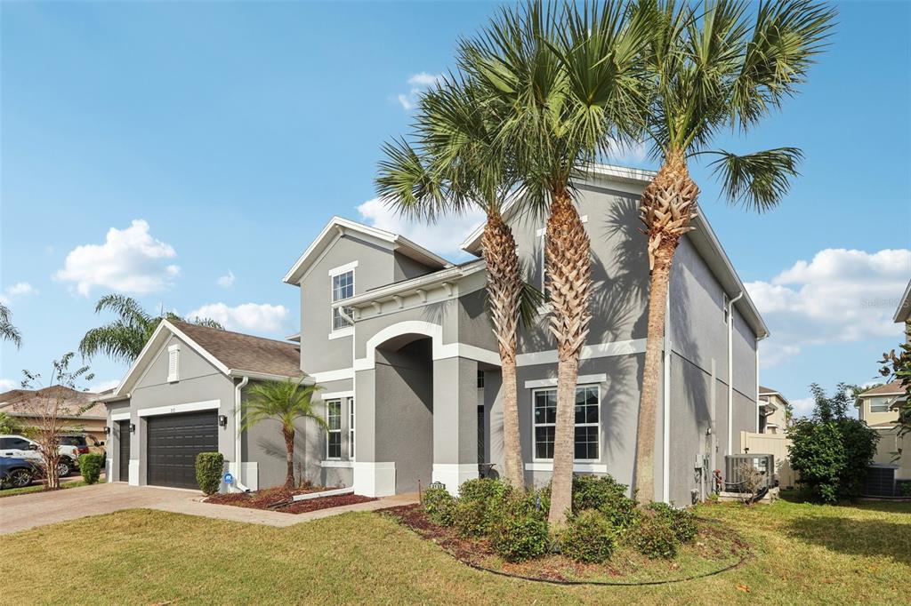 A two-story gray house with a dark garage, palm trees, and a landscaped front yard — 2132 PLANTATION OAK DRIVE, ORLANDO, FL