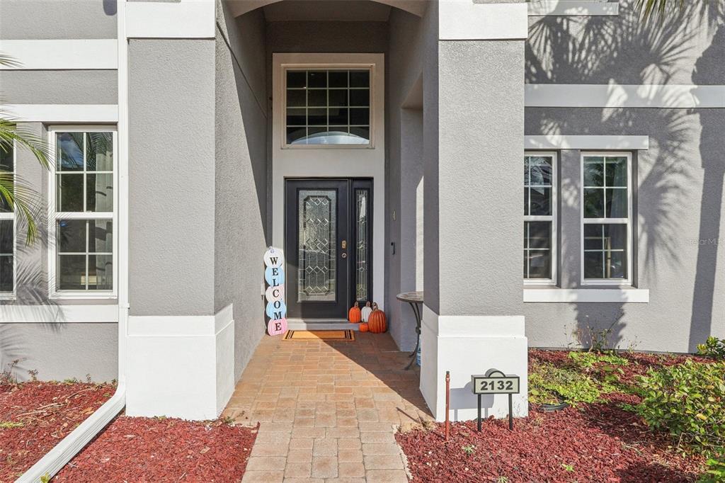 The exterior of a gray house features a brick walkway leading to a front door — 2132 PLANTATION OAK DRIVE, ORLANDO, FL