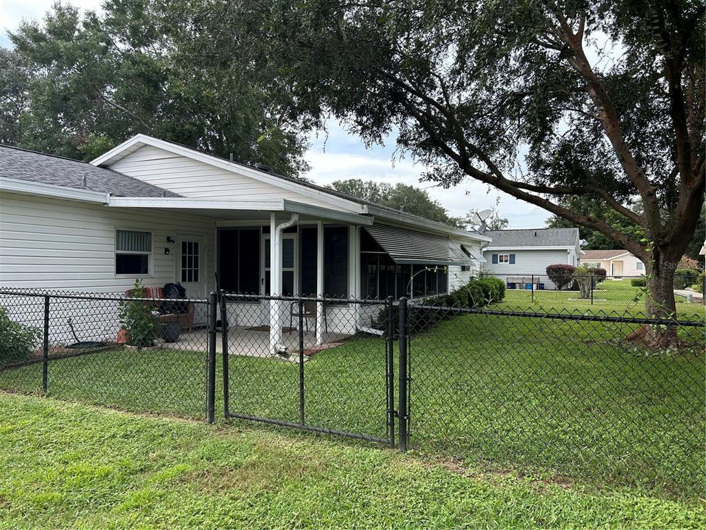A white house with a screened-in porch and a chain-link fence in the backyard — 17513 SE 95TH COURT, SUMMERFIELD, FL