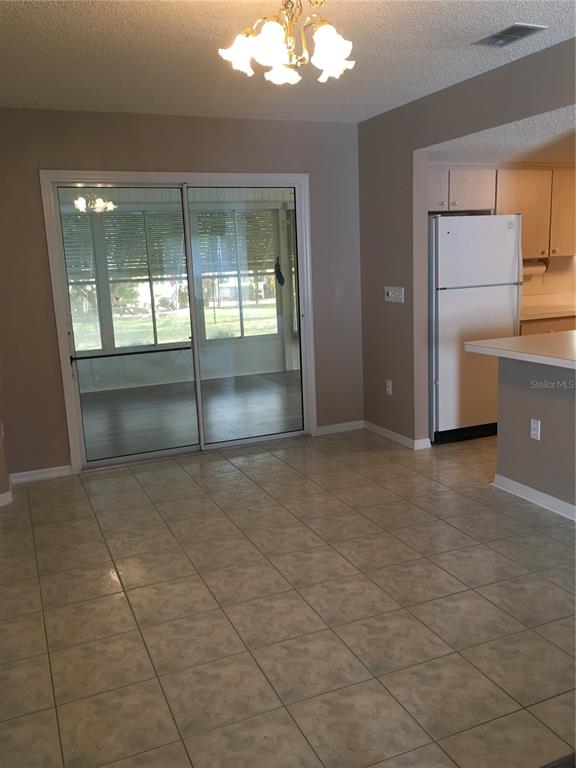 A dining area with tile flooring, a sliding glass door, and an adjacent kitchen — 17513 SE 95TH COURT, SUMMERFIELD, FL