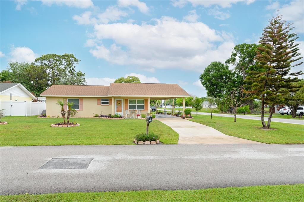 A single-story house with a tan exterior, a brown roof, and an attached carport — 2300 3RD STREET, ST CLOUD, FL
