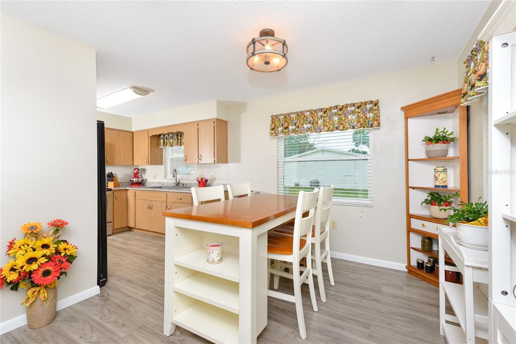 A kitchen with light wood cabinets, a central island, and a dining area with a window — 2300 3RD STREET, ST CLOUD, FL