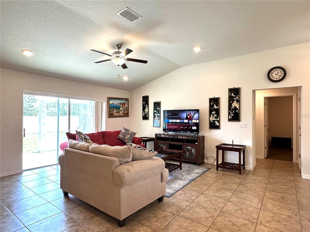 An open-concept living room and kitchen featuring tile floors, a ceiling fan, and dark cabinetry — 15211 SW 65TH TERRACE ROAD, OCALA, FL