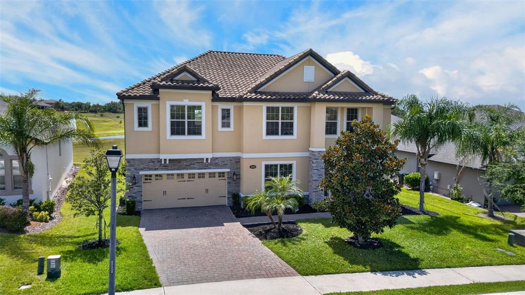 A two-story suburban house with a tan stucco exterior, stone accents, and a tiled roof — 2468 VERDE VIEW DRIVE, APOPKA, FL