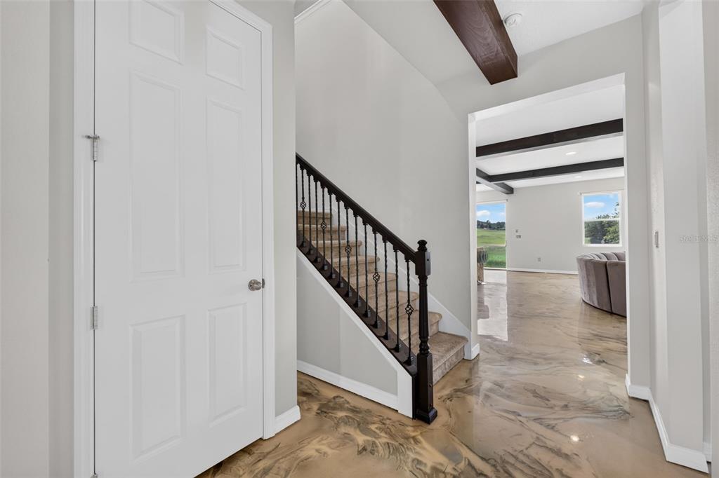 An entryway features a carpeted staircase with dark railings, light walls, and glossy epoxy flooring — 2468 VERDE VIEW DRIVE, APOPKA, FL
