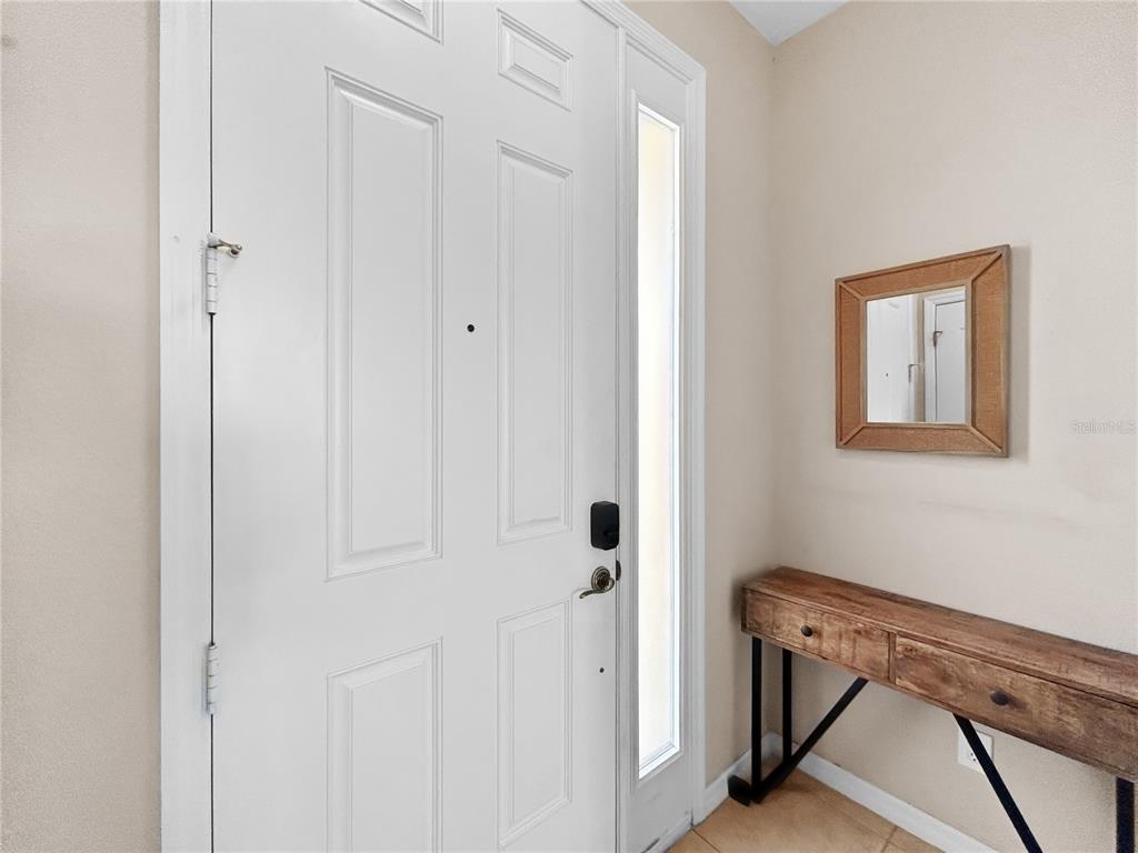 A white front door with a side window stands next to a wooden console table — 755 MAROTTA LOOP, OCOEE, FL