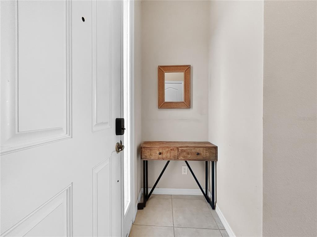 An entryway features a white door, a wooden console table, and a small wall mirror — 755 MAROTTA LOOP, OCOEE, FL
