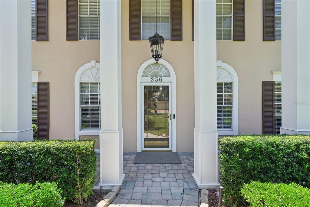The exterior of a house features a front door with a transom window and columns — 236 S SHADOWBAY BOULEVARD, LONGWOOD, FL
