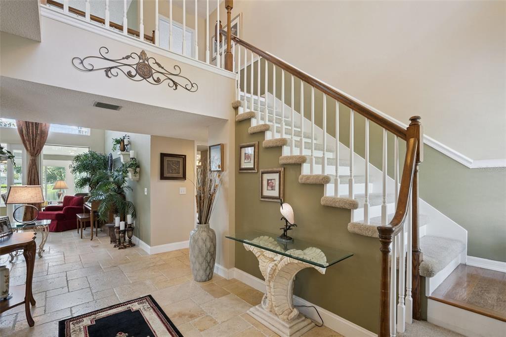 A foyer features a carpeted staircase with a wooden railing and a stone-tiled floor — 236 S SHADOWBAY BOULEVARD, LONGWOOD, FL
