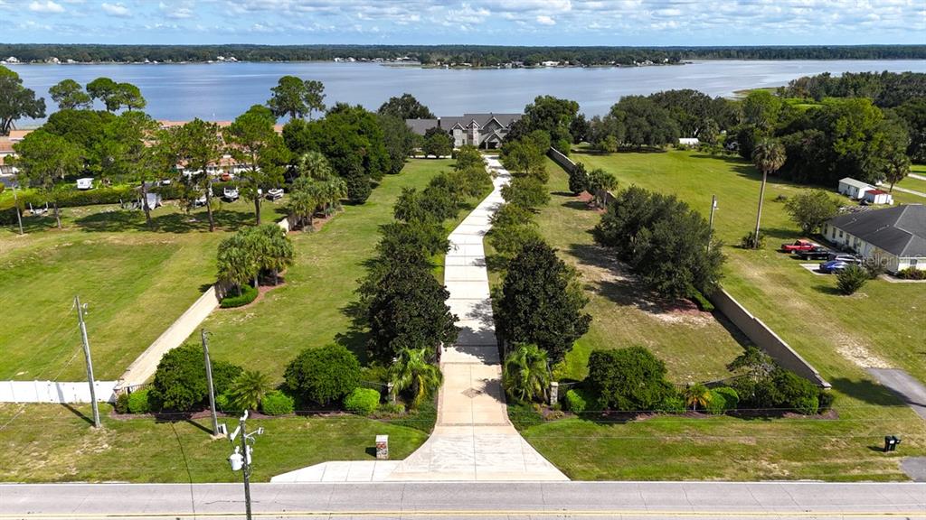 An aerial view shows a long concrete driveway leading to a house near a lake — 11035 SE SUNSET HARBOR ROAD, SUMMERFIELD, FL