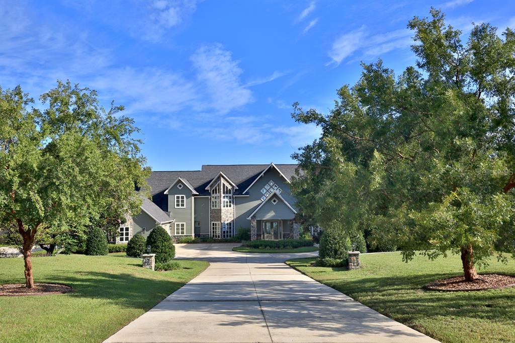 A large two-story house with green siding and stone accents sits at the end of a driveway — 11035 SE SUNSET HARBOR ROAD, SUMMERFIELD, FL