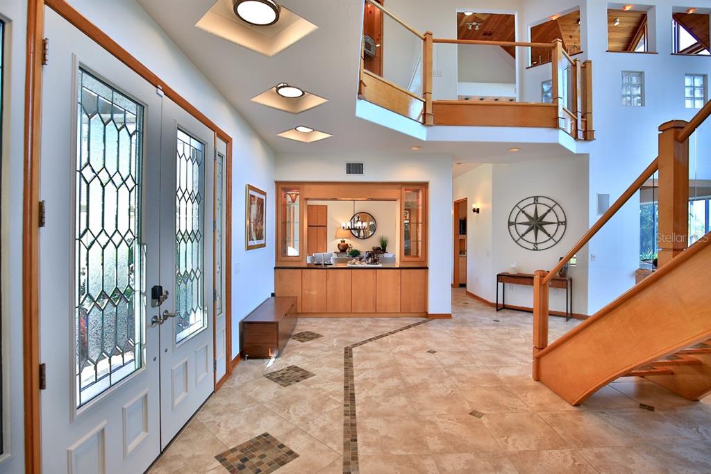 A bright foyer features tile flooring, a wooden staircase, and a built-in wet bar area — 11035 SE SUNSET HARBOR ROAD, SUMMERFIELD, FL
