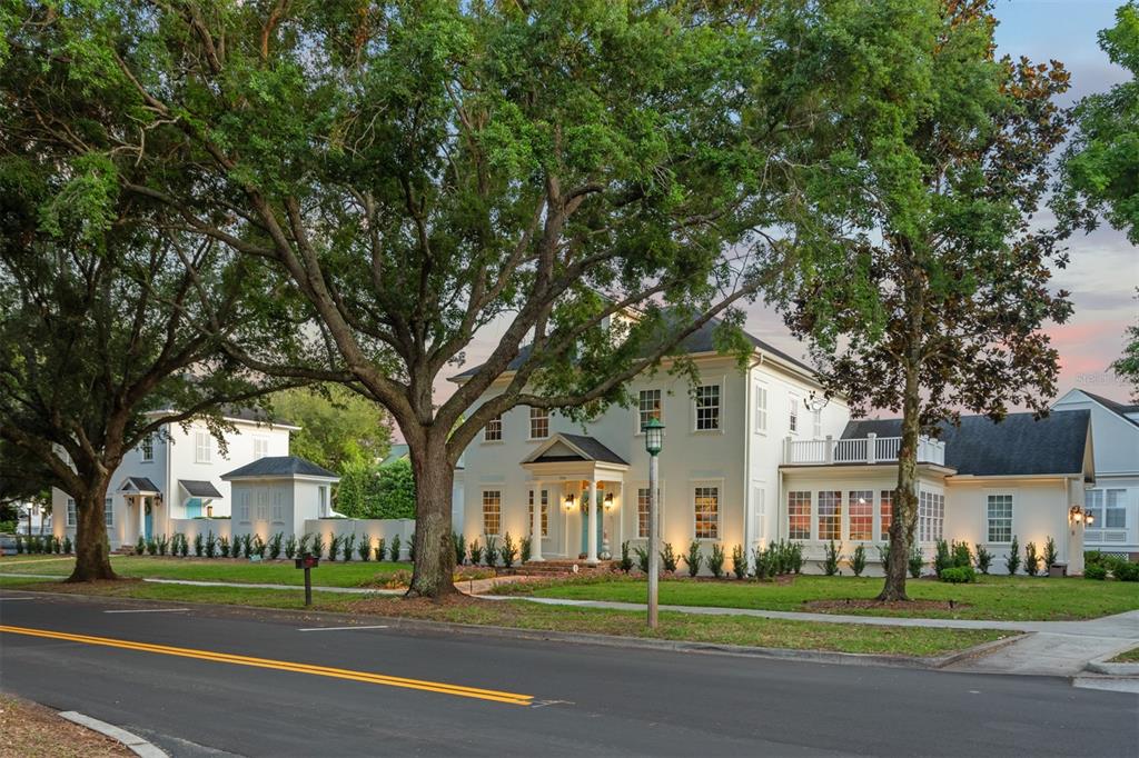 A two-story white house with a columned porch stands behind large trees along a street — 706 GOLFPARK DRIVE, CELEBRATION, FL