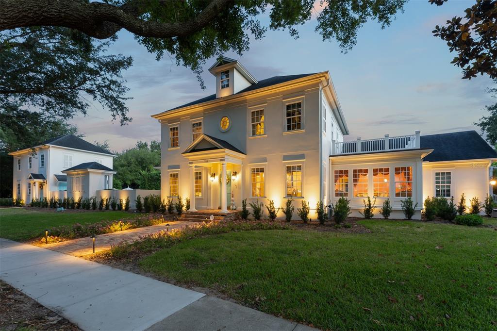 A two-story white house with a columned entrance, brick walkway, and a detached garage — 706 GOLFPARK DRIVE, CELEBRATION, FL